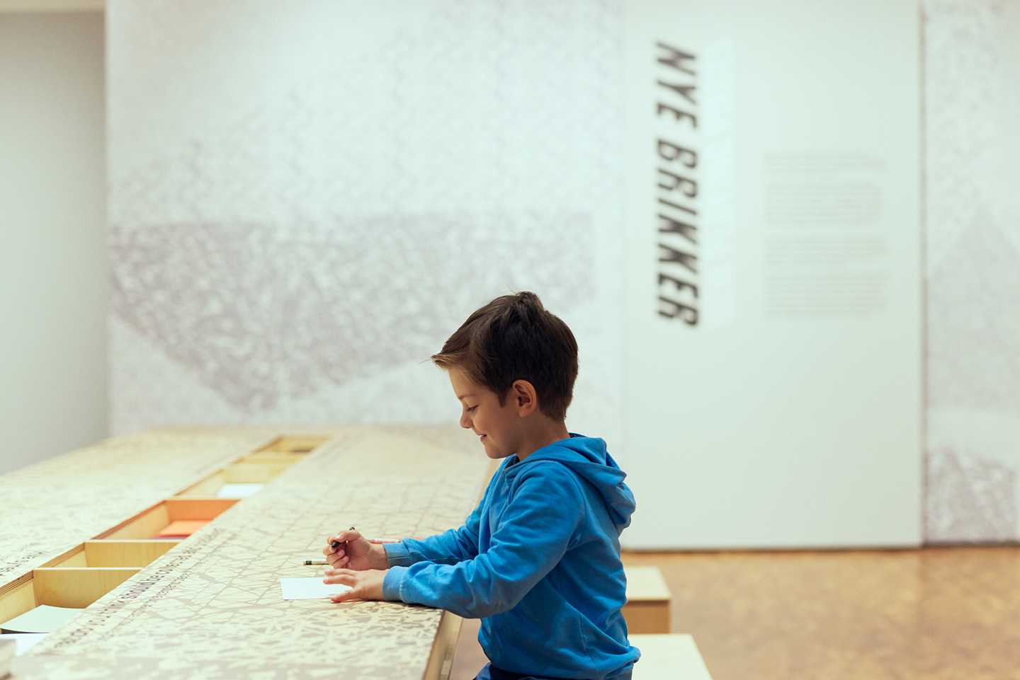 A boy drawing his thoughts in the exhibition Playing Pieces. Photo: Pernille Sandberg