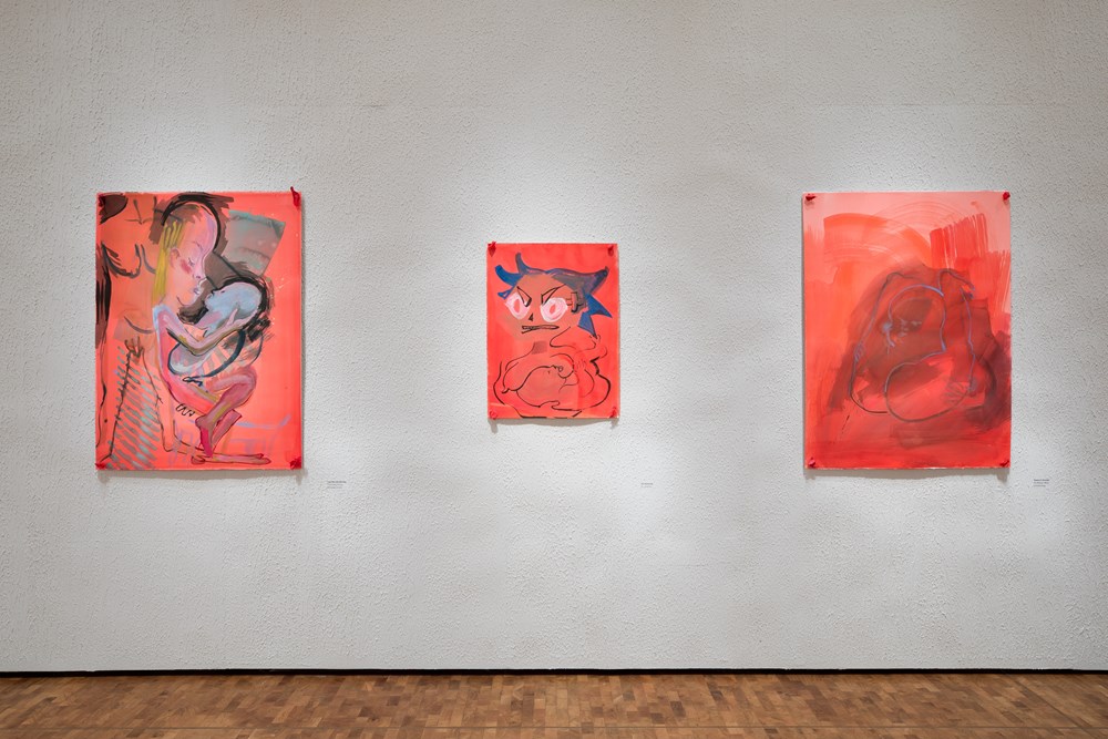 Installasjonsbilde fra utstillingen CAMILLE HENROT – MUNN TIL MUNN. Tre røde kunstverk uten rammer montert på en betongaktig vegg. 