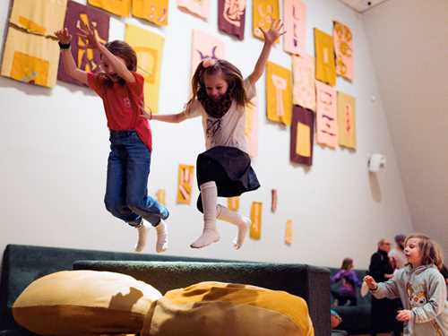 Barn leker i Kaoskammeret, to barn tar sats og hopper ned i et fargerikt putehav