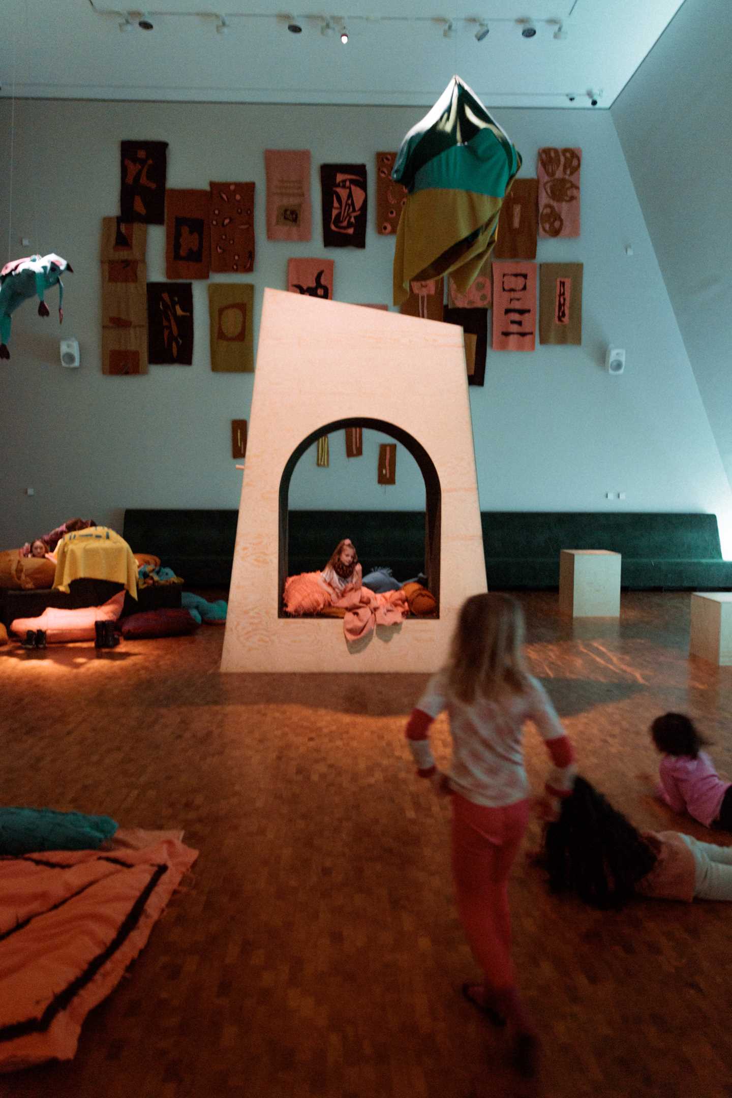 Kids playing in The Chamber of Chaos, a wonderful world of portals, colourful pillows and textile figures, surrounded by magical lighting