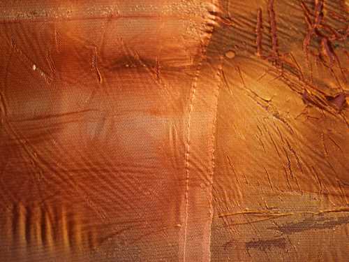 A close-up of a thick, viscous and partially transparent material in warm brown-orange colours.