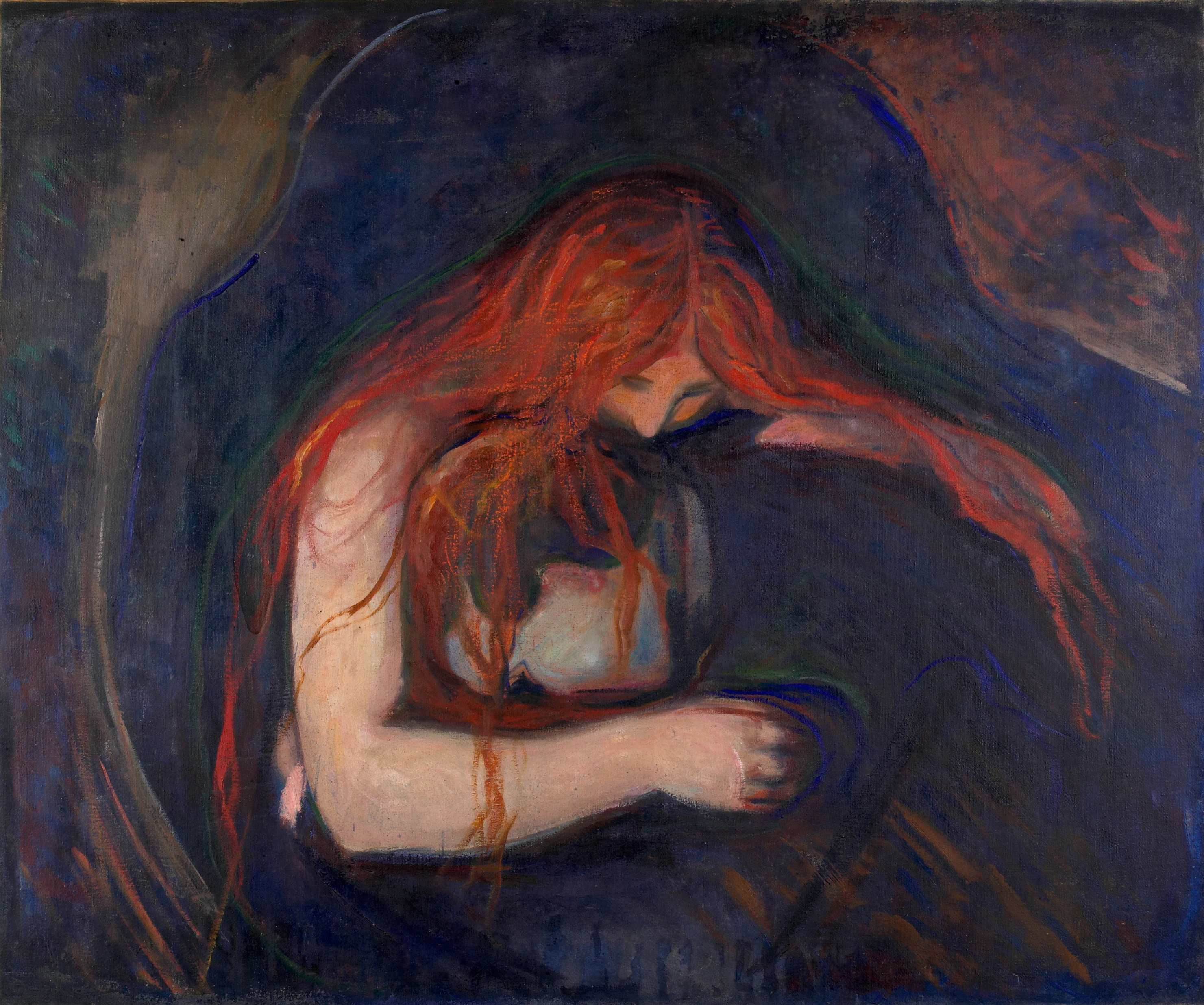 A man buries his head in a woman’s lap. She embraces him, placing her mouth on the back of his neck. Her blood-red hair is draped around the man’s body. The room around them is dark. 