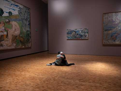 To dansere omfavner hverandre sittende på gulvet omgitt av Edvard Munchs monumentale verk. 