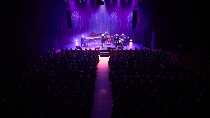 Jazz musicians on stage in a full concert hall